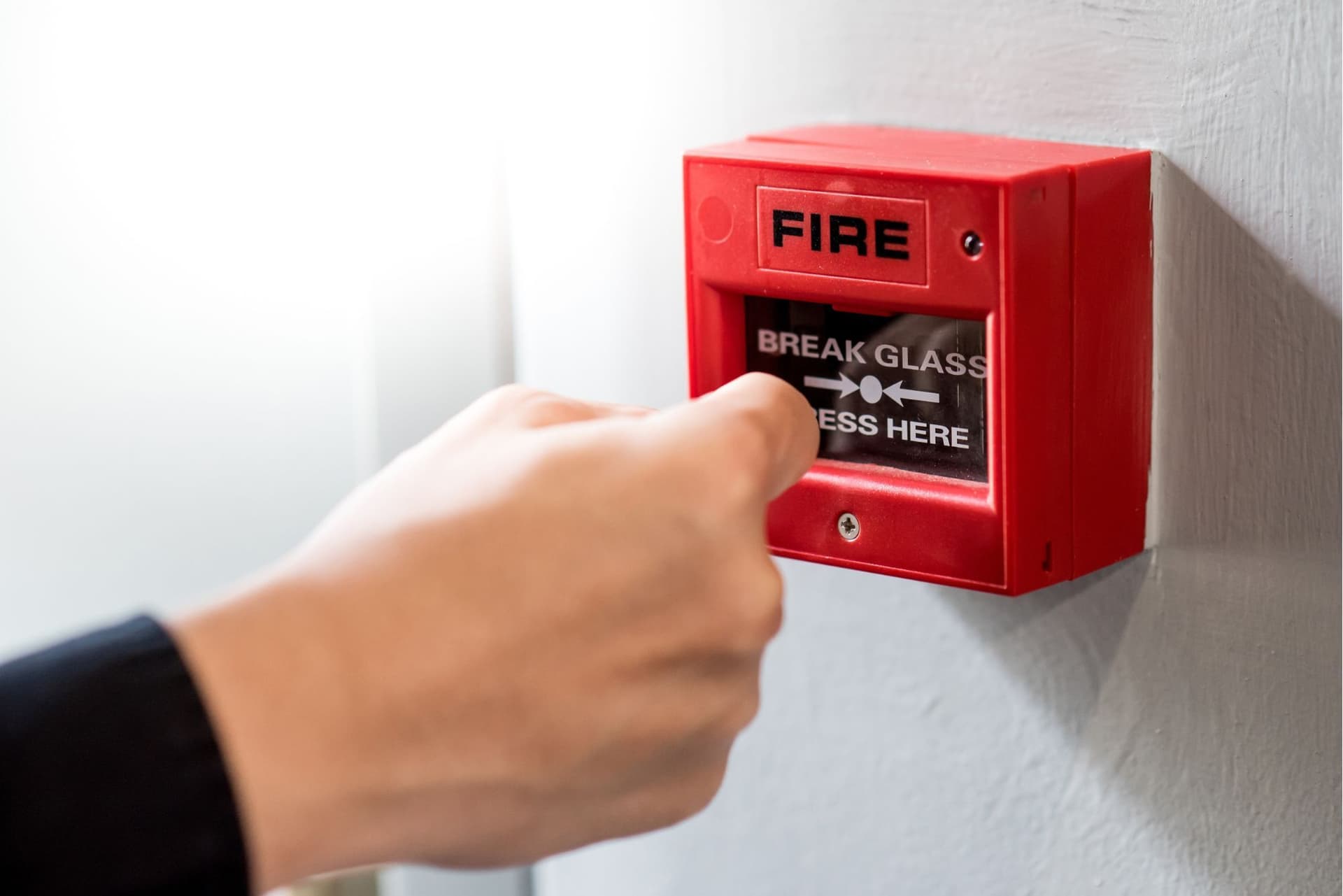 Persoon slaat een brandalarm in bij een noodsituatie.